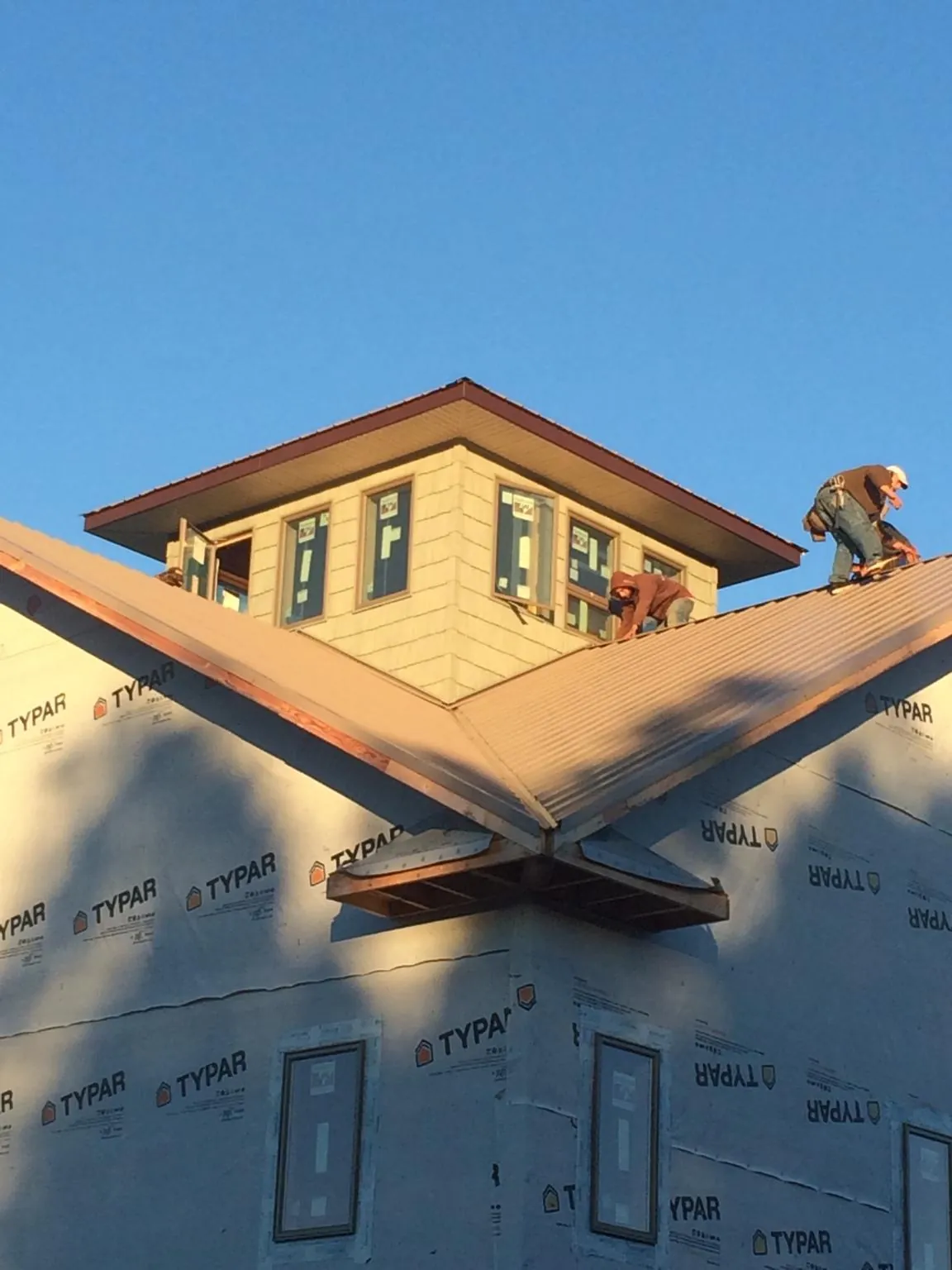Roofers working around a rooftop cupola on a new metal roof at sunset — Roof Waterproofing in Honolulu by Roofing Brothers
